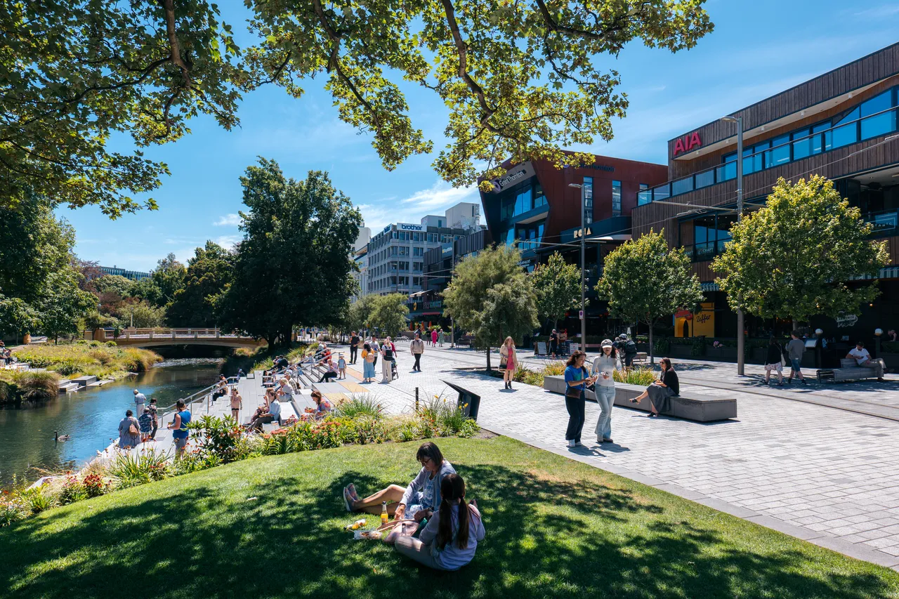 People relaxing beside the Ōtākaro Avon River at The Terrace in central Christchurch